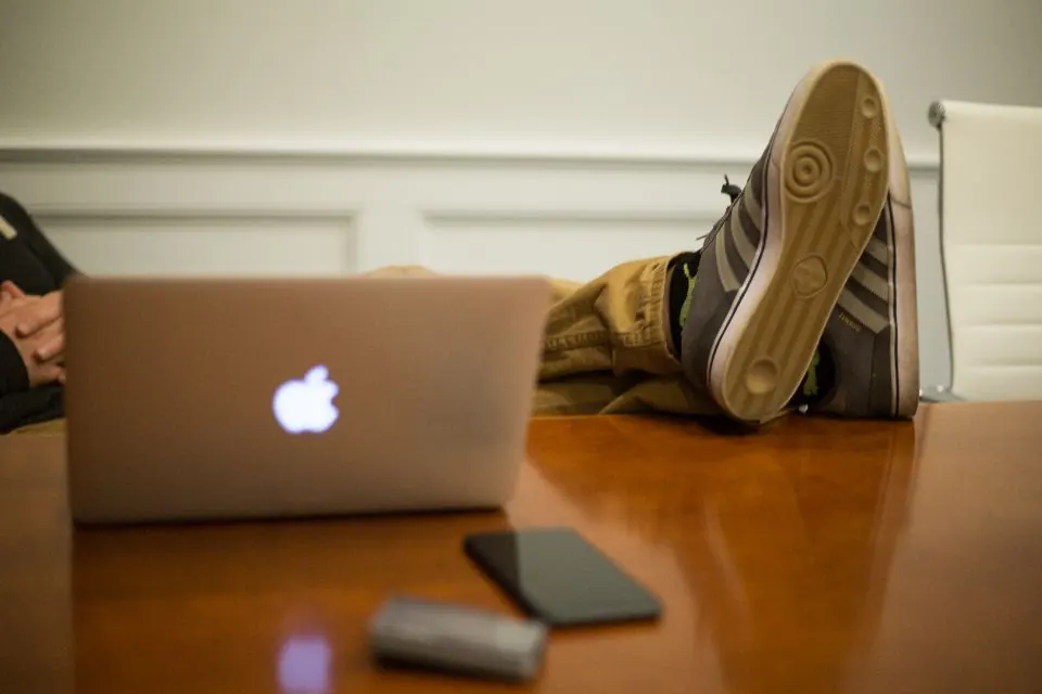 Persona relajada con los pies sobre el escritorio junto a su portátil